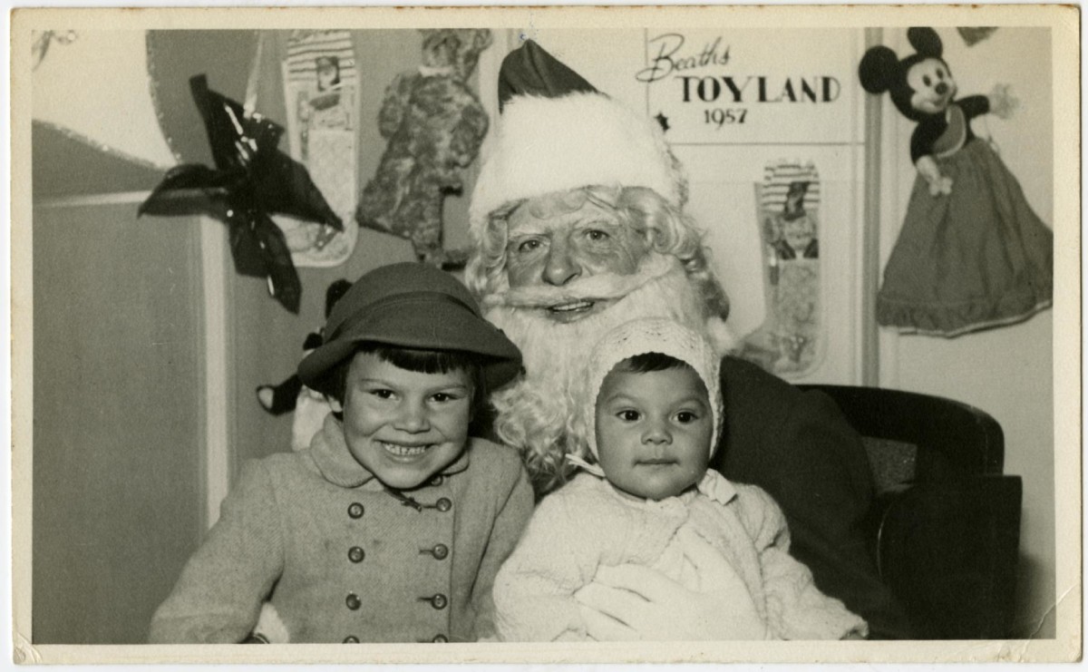 Black and white photo of two children sitting on Santa's knee, 1957