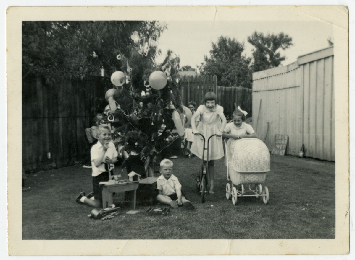 Black and white photo of children and a Christmas tree in a suburban backyard